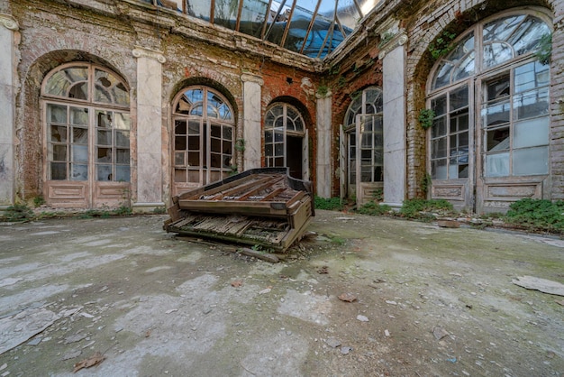 Broken old wooden grand piano in the middle of ruins of an abandoned medieval building