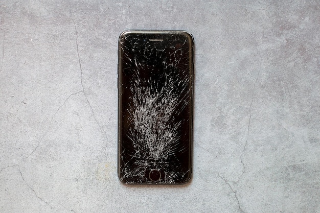 Broken phone screen on grey background dropped mobile phone on
the ground and smashed the screen