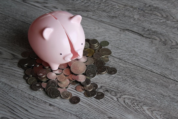 Broken piggy bank and coins on wooden table with copy space\
financial concept