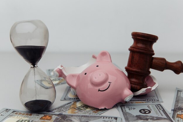 Broken piggy bank, hourglass and judge gavel.