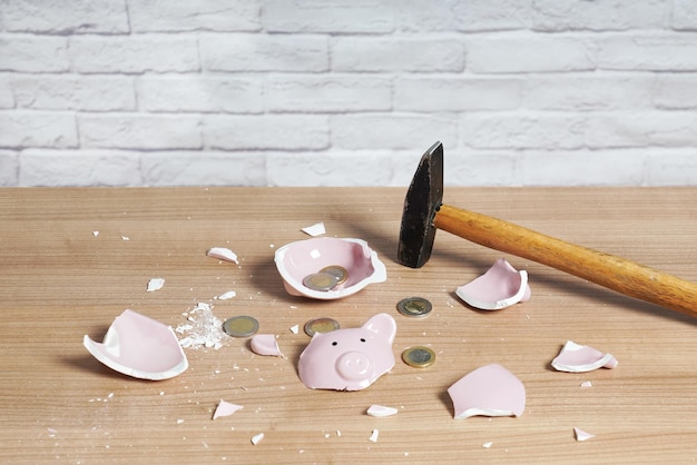 Broken Piggy bank smashed into pieces with hammer and small change