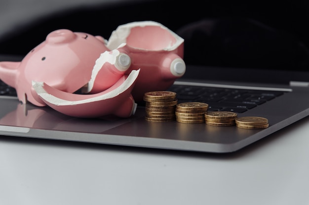 Broken piggy bank and stack of coins on a keyboard