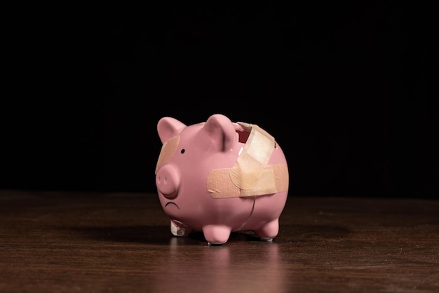 Photo broken piggy bank with band aid bandage or plaster finance background concept for economic recession or bankruptcy