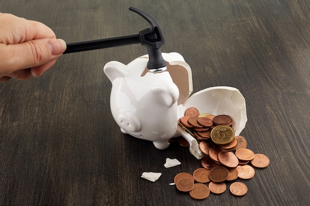 Broken piggy bank with cash and coins on wooden background