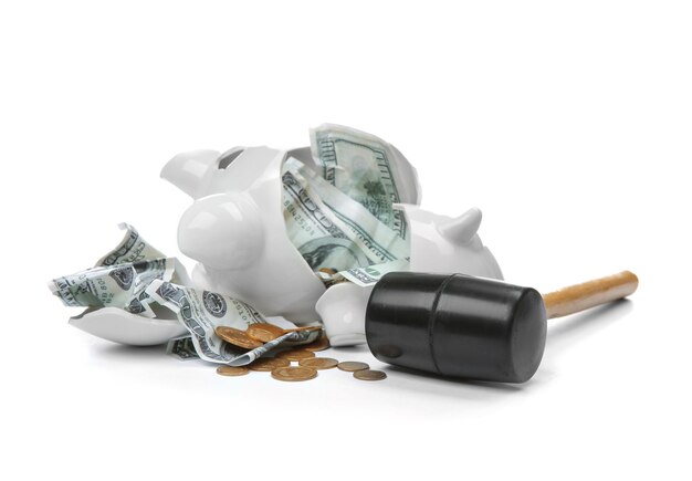 Broken piggy bank with money and hammer on white background