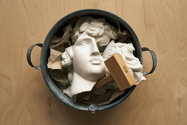 Broken plaster head in a metal basin.