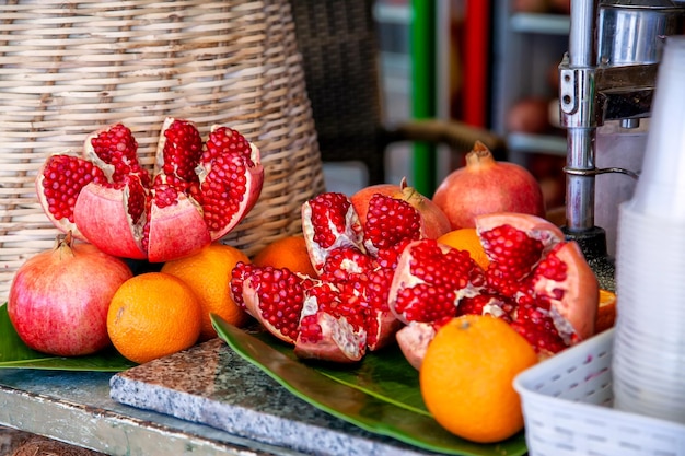 Фото Сломанные плоды граната и целые апельсины и гранаты, приготовленные для свежевыжатого сока на прилавке уличной торговли.