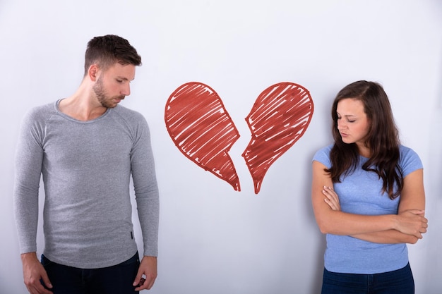 broken red heart between sad couple