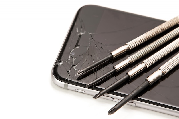 Broken smartphone and small screwdrivers for repair