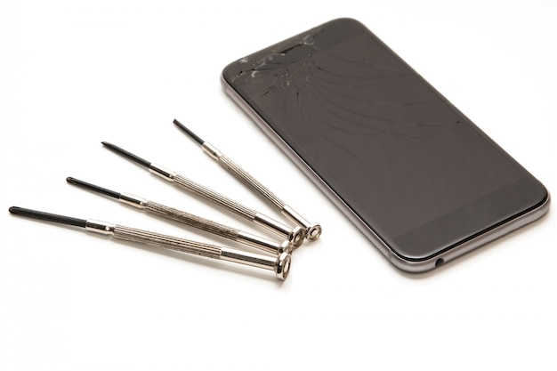 Broken smartphone and small screwdrivers for repair