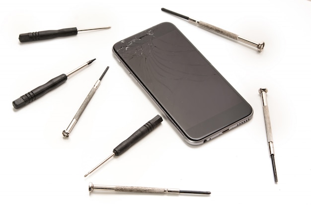 Broken smartphone and small screwdrivers for repair