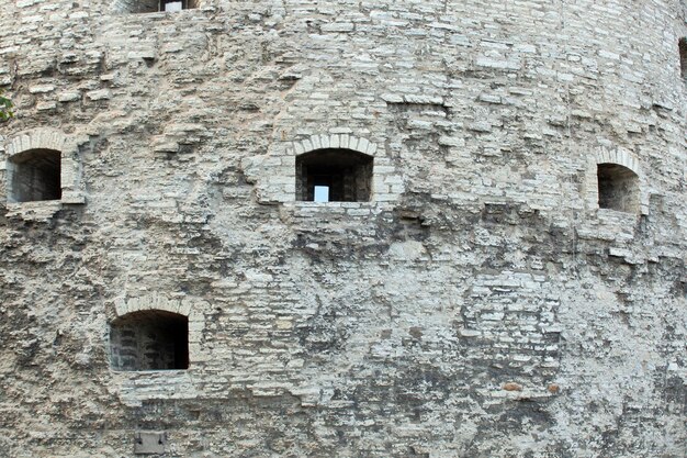 Photo broken stone texture on ancient gray wall with arched window in tallinn background template