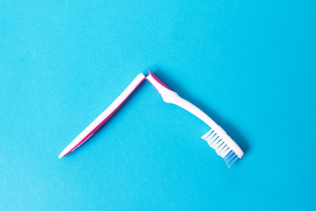 Broken toothbrush on blue background close up