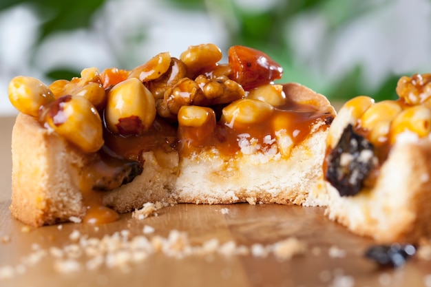 Broken with crumbs tartlet round shape with nuts and dried fruits poured with caramel, used for cooking hazelnuts, peanuts, walnuts, tartlet dough flows sweet caramel