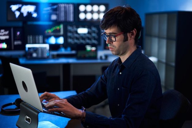 Photo broker trader business man working on laptop in a corporate office multiple monitors at background