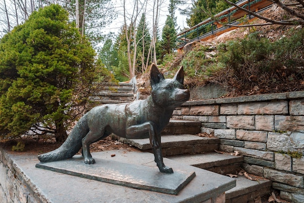 Photo bronze fox statue on stone pedestal in park setting overcast sky late autumn ambiance