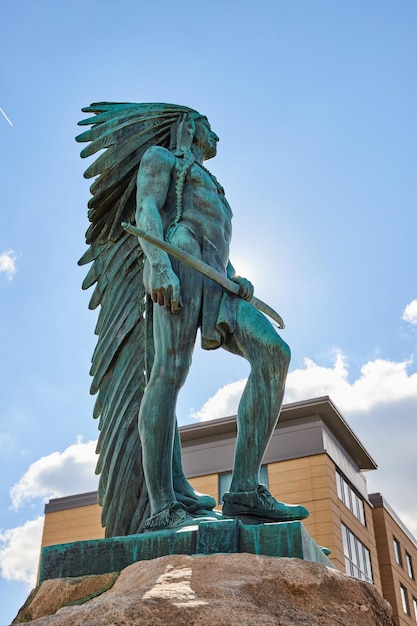 Bronze Native American Warrior Statue with Urban Backdrop LowAngle View