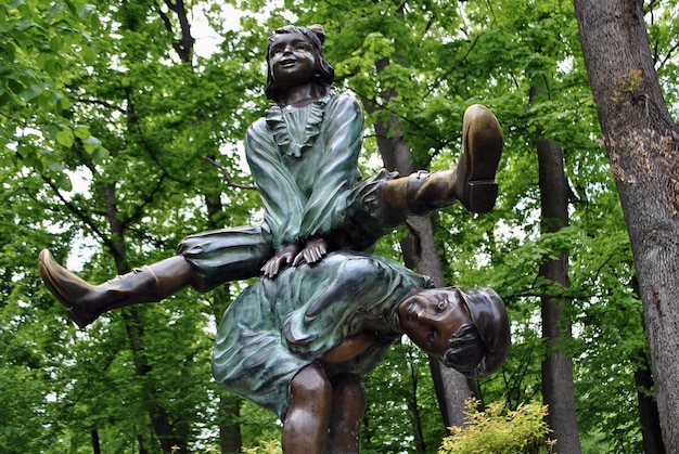 Bronze sculpture in the form of a playing girl jumping over a tilted boy against the background