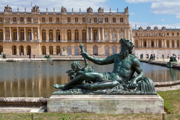 Bronze statue on the edge of a basin in the gardens of Versailles