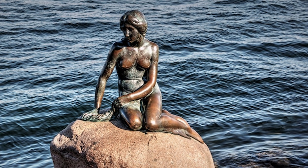 bronzen beeld van zeemeermin aan zee