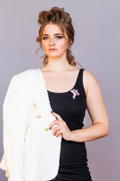 a brooch in the form of a bouquet of lilac flowers on a black tshirt of a brunette girl the girl is posing on a gray background smiling and looking at the camera