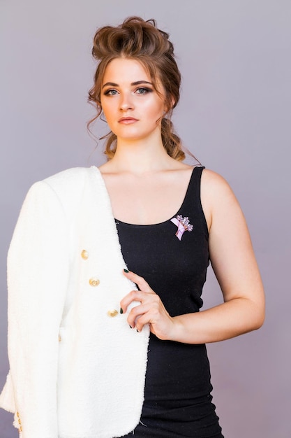 A brooch in the form of a bouquet of lilac flowers on a black Tshirt of a brunette girl The girl is posing on a gray background smiling and looking at the camera