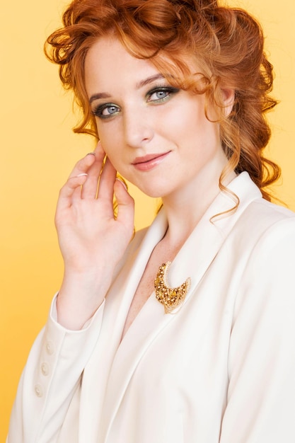 Brooch of golden color in the shape of the moon on a white jacket of a redhaired girl