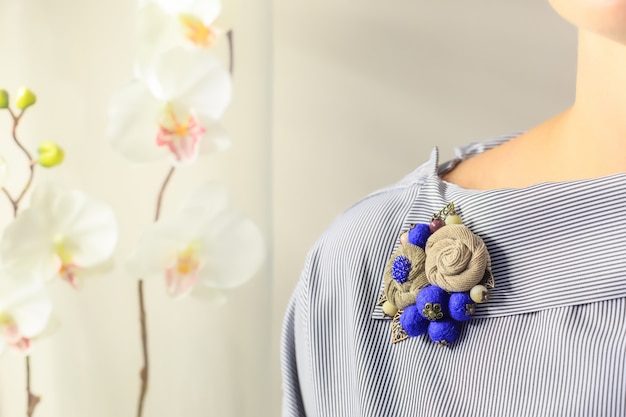 Brooch handmade in the form of flowers beige and blue color is attached to the female blouse