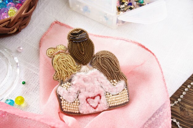 Brooch Mom and daughter handmade beads on table on pink background