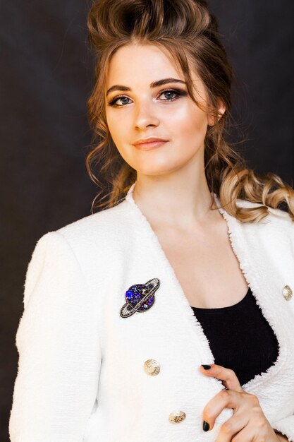 brooch in the shape of a planet with a ring on a young woman's white jacket