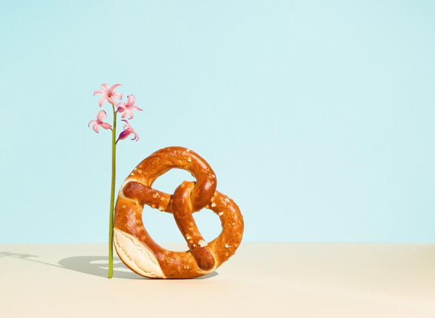 Brood bagel in hartvorm met sesamzaadjes en roze hyacint op blauwe achtergrond Minimal food idea