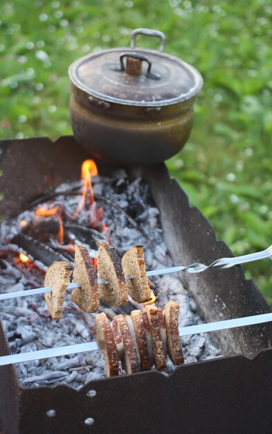 Brood en vlees aan het spit. Oude pan met kruidenthee op koperslager.