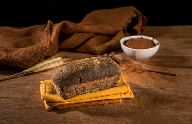 Brood gemaakt met cacau en chocolade op gele doek op rustieke houten tafel met ingrediënten.