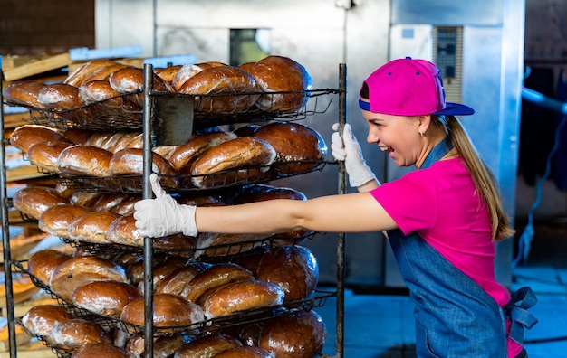 Brood in de handen van een bakker op de achtergrond van een industriële oven. industriële broodproductie