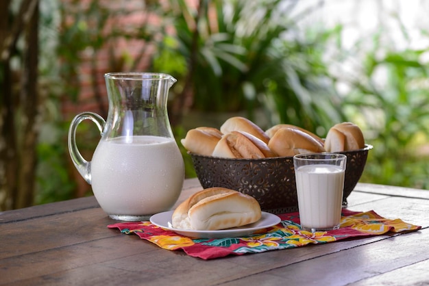 Foto brood in een mand en melk in een glazen kruik op een houten tafel