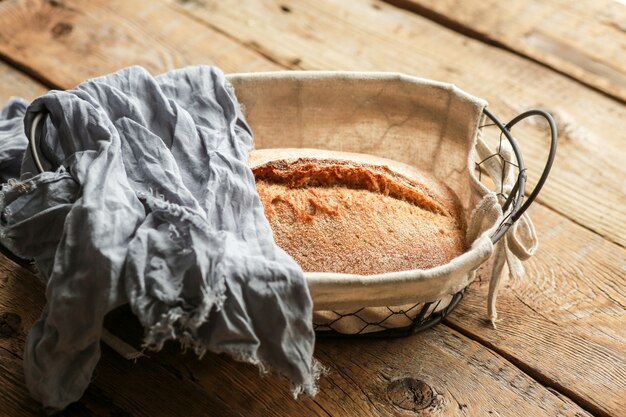 Foto brood in een mand op een zwarte ondergrond. geassorteerde brood in een metalen mand. plaats voor recept en tekst. bak brood met een deegroller en bloem. roggebrood, boekweitbroodjes en stokbrood met zaden.