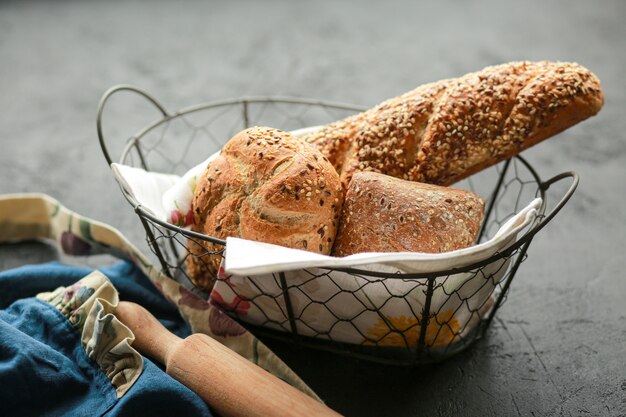 Brood in een mand op een zwarte ondergrond. Geassorteerde brood in een metalen mand. Plaats voor recept en tekst. Bak brood met een deegroller en bloem.