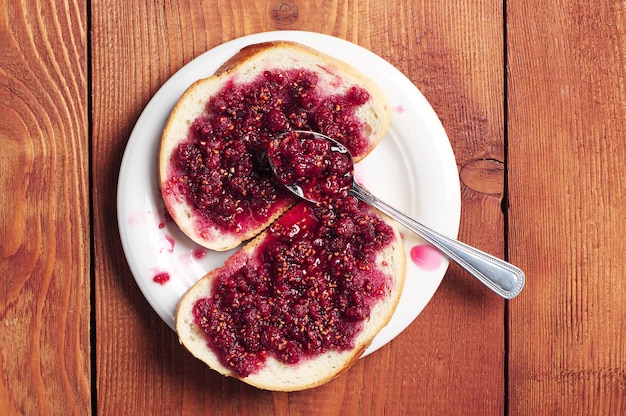 Brood met frambozenjam op bruine tafel. bovenaanzicht