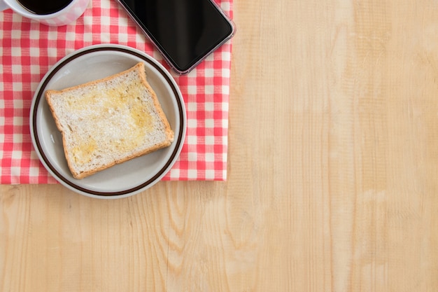 Brood met suiker en boter en smartphone op houten lijst hoogste mening