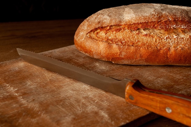 Brood op een bord op een donkere achtergrond brood gebakken met een korst warm met mes