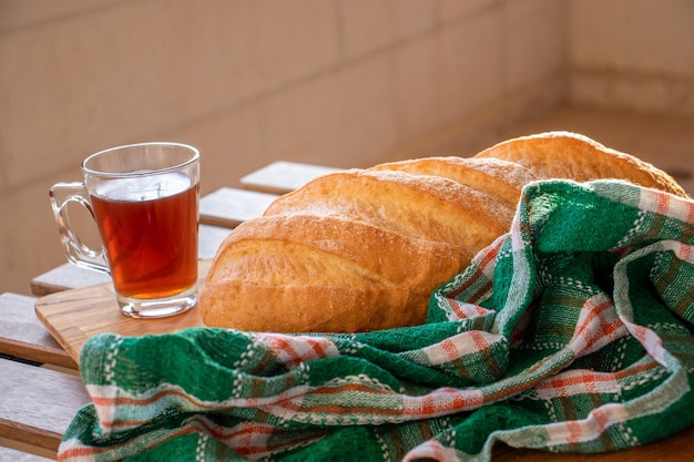 Brood op houten tafel klaar om te worden geserveerd en kopje thee op witte achtergrond