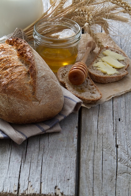 Brood, rogge, tarwe, honing, melk rustieke houten achtergrond