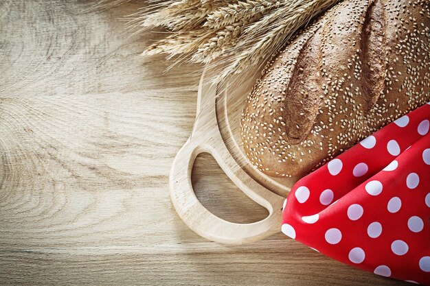 Brood snijplank rogge oren rood tafelkleed op houten achtergrond