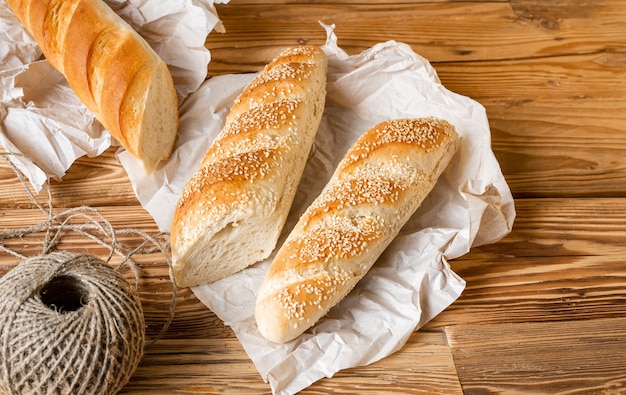 Brood stokbrood besprenkeld sesam sesam met inpakpapier op houten tafel