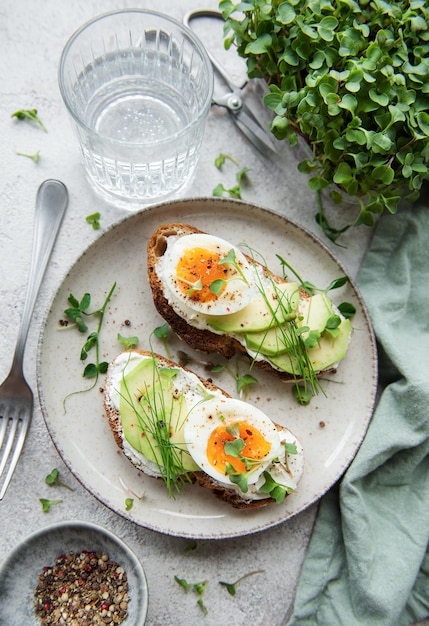 Brood toast gekookte eieren avocado slice microgreens op een bord