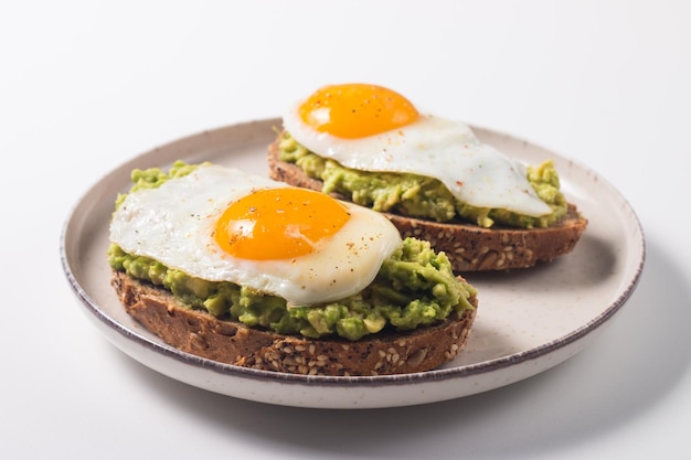 Broodje avocado-ei met een glas water. Gezond licht ontbijtconcept. Volkoren toast met