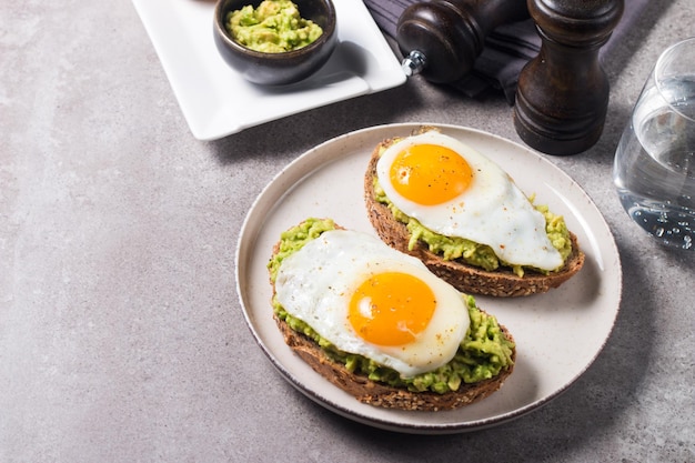 Broodje avocado-ei met een glas water. gezond licht ontbijtconcept. volkoren toast met