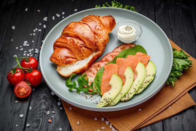 Broodje Croissant met zalmroomkaas, avocado en groenten Serveren in een café Foto voor het restaurantmenu