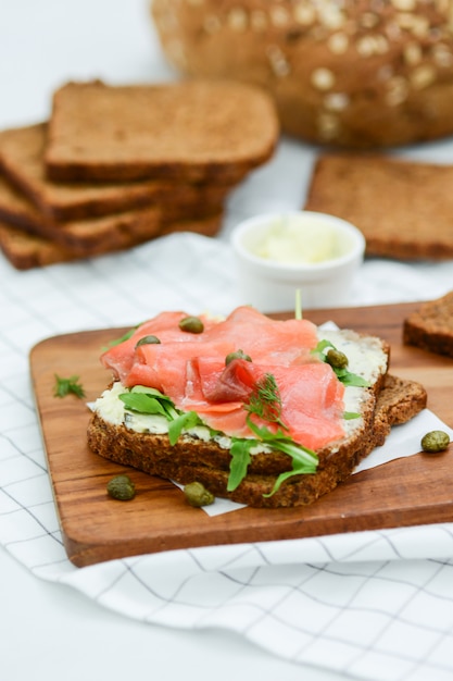 Broodje gerookte zalm met kaas, pistache en slablaadjes, bruin brood