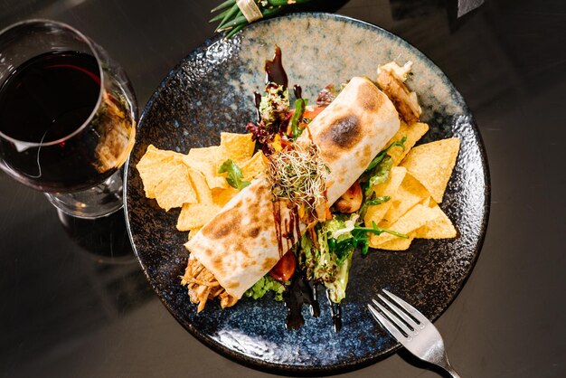 Broodje gevuld met pulled pork met groene salade en frietjes op donkere ondergrond